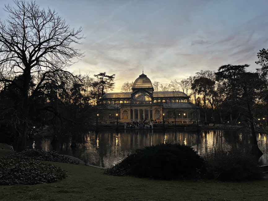 A glass building reflected in a lake and surrounded by trees