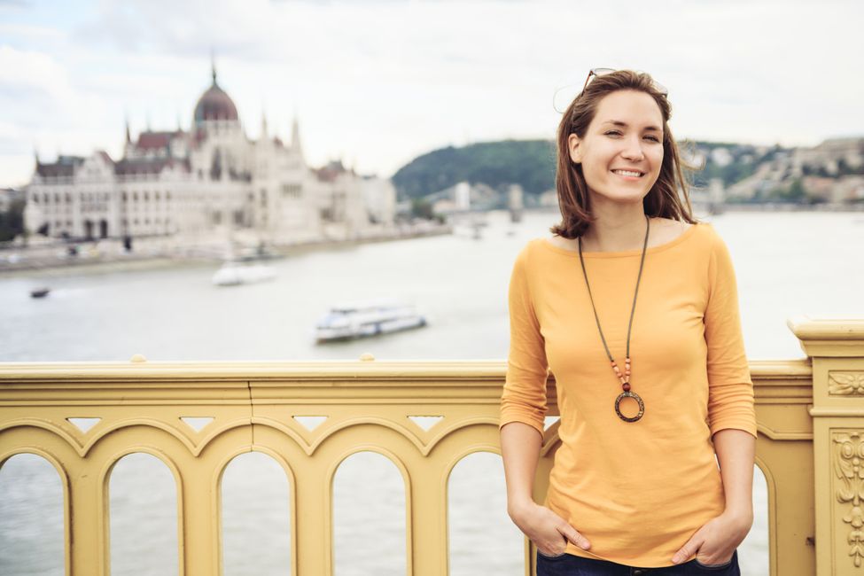 Young woman standing on bridge with parliament in background in Budapest