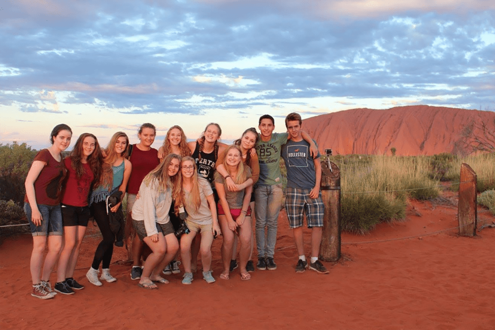 High school students smiling with the red mountains of Australia behind them