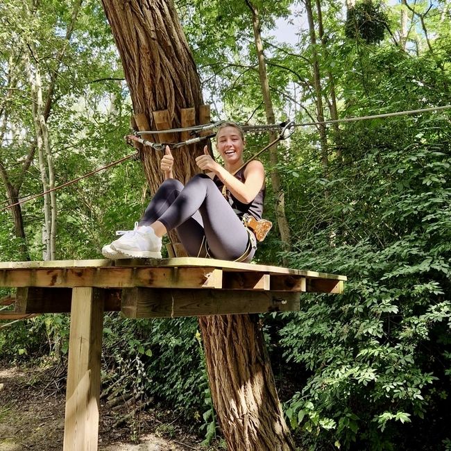 A participant is sitting on the platform after finishing a zipline. 