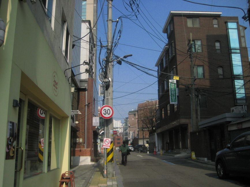 lone street in seoul with so much street wiring visible and one person walking ahead 