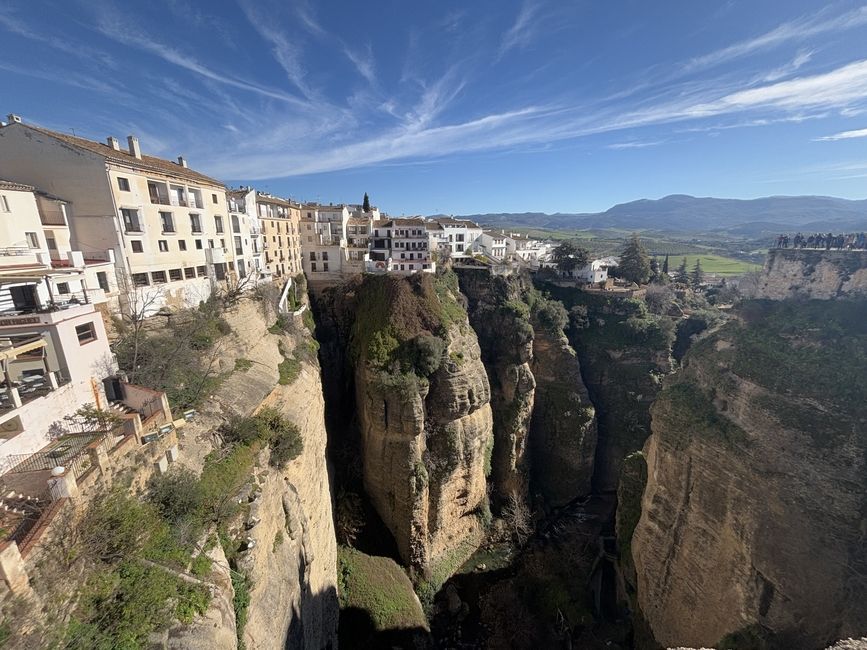 A view of whitewashed houses and a deep gorge from the top of El Puente Nuevo in Ronda, Spain