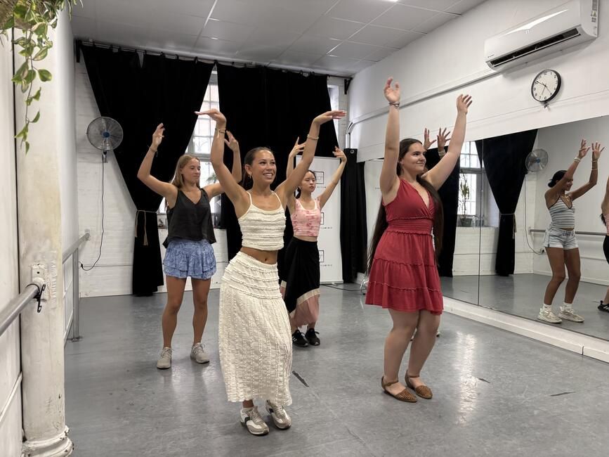 Group of students dancing flamenco with their arms up in the air