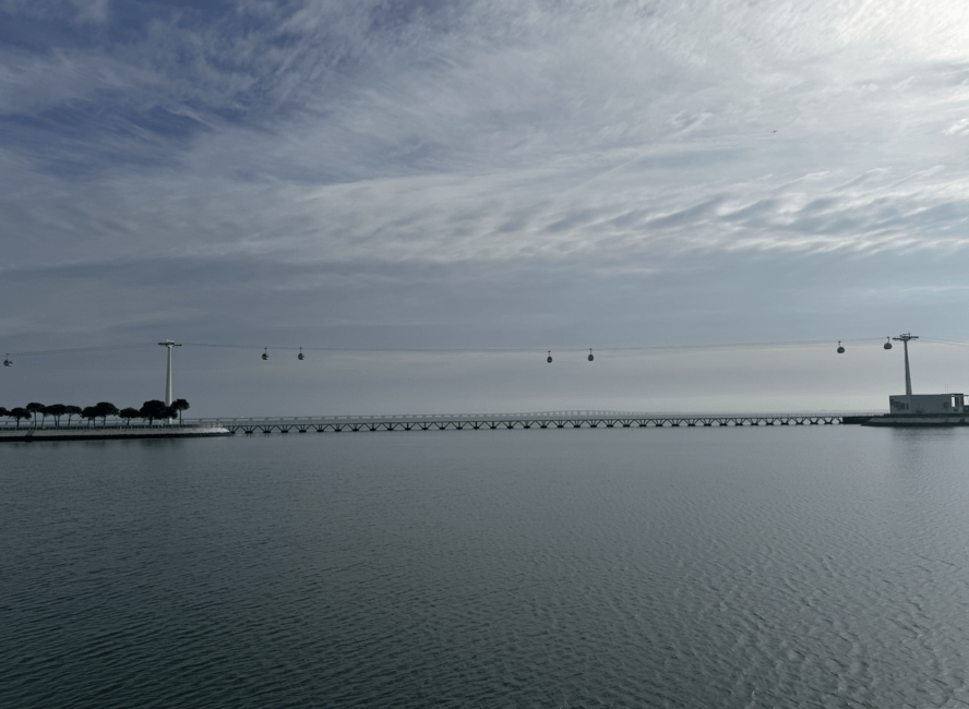 Calm waters, cloudy skies, and cable cars at Parque das Nações.