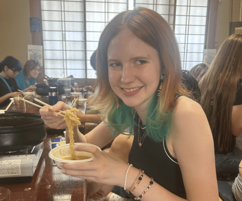 student smiling with newly made noodles