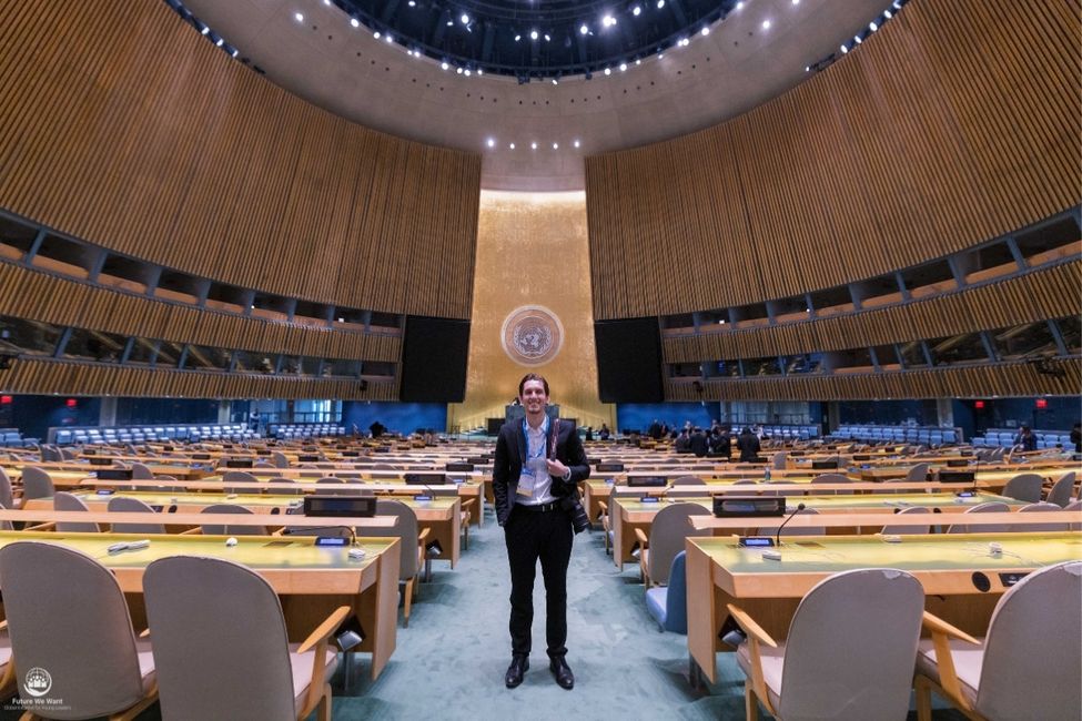 Rodrigue stands in the middle of the United Nations General Assembly Hall.
