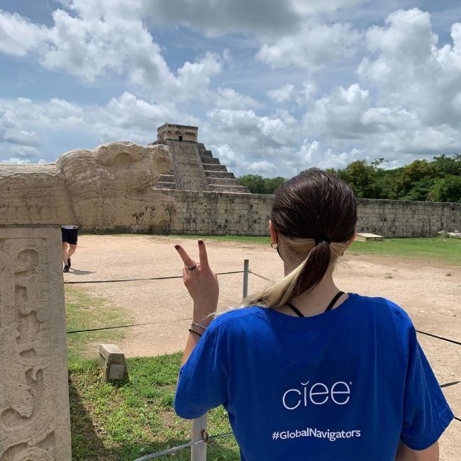 Global Navigator making peace sign by ancient pyramid in Yucatan