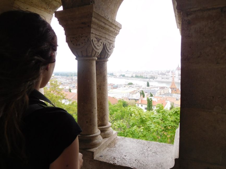 Pensive woman looking out columned window at Budapest