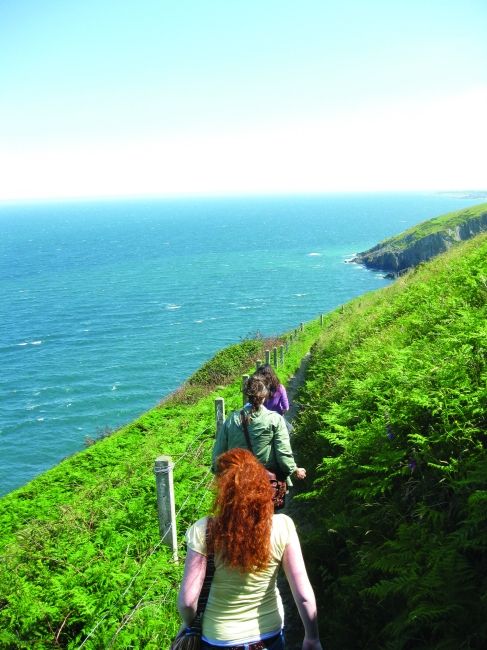 Red headed student hiking in Ireland by the ocean