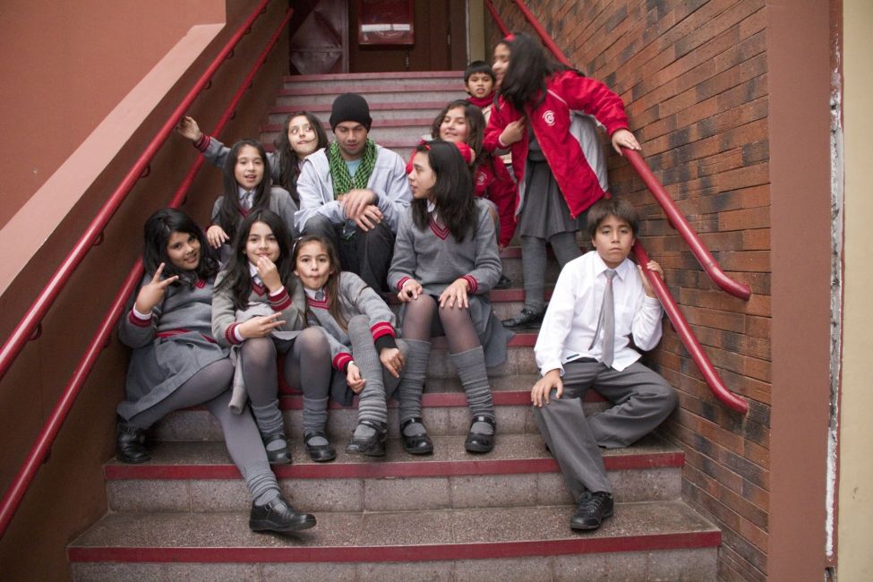 Teach in Chile participant sitting on the steps with Chilean students at school