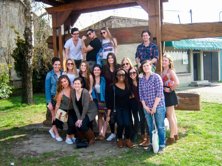 Prague students standing in front of wooden frame