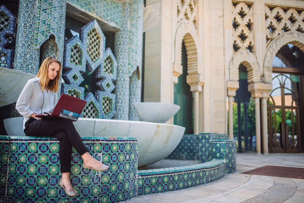 Seville student intern working on laptop by a fountain