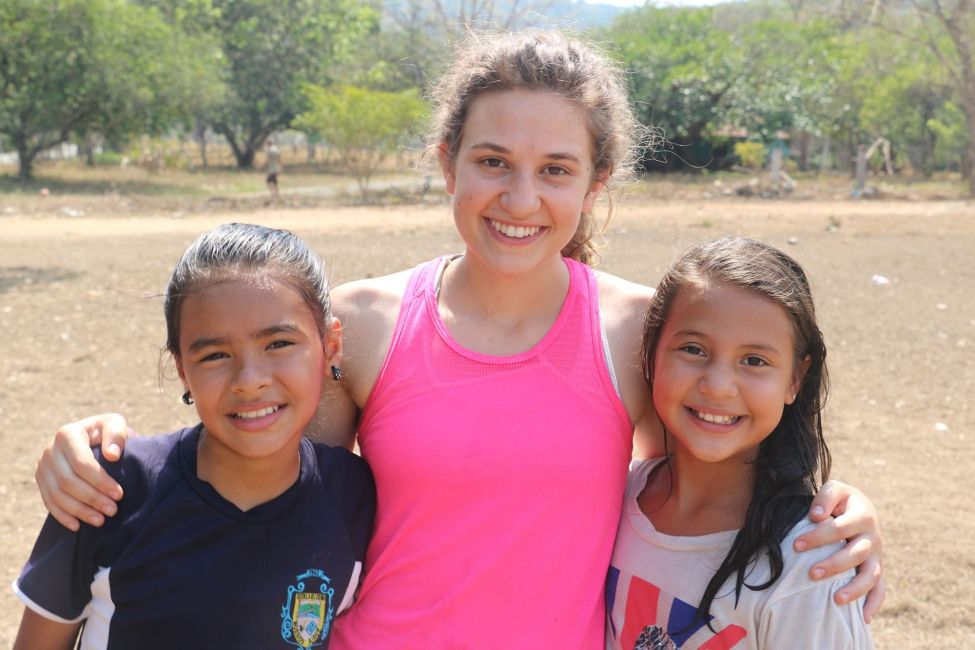 Young woman hugging kids outside