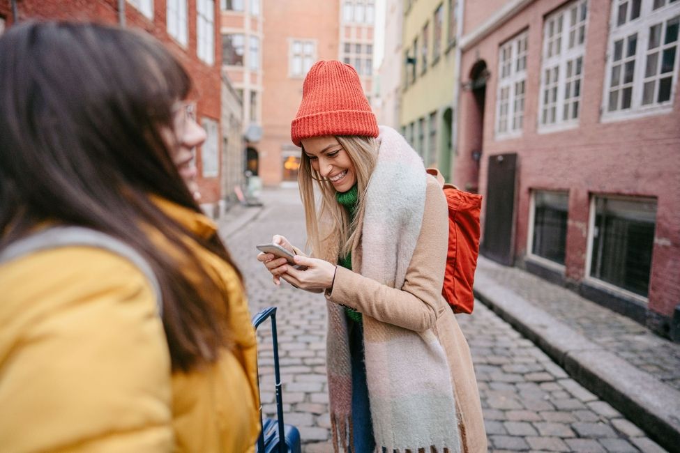 copenhagen girl in alley with her luggage looking at cell phone