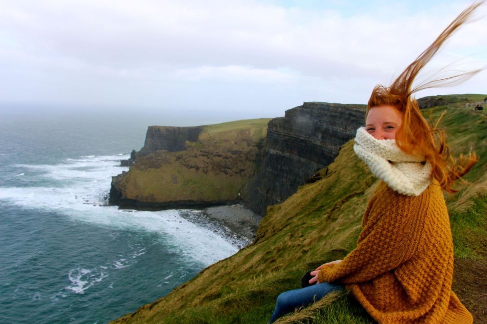 dublin redheaded girl on cliffs with her hair blowing straight up