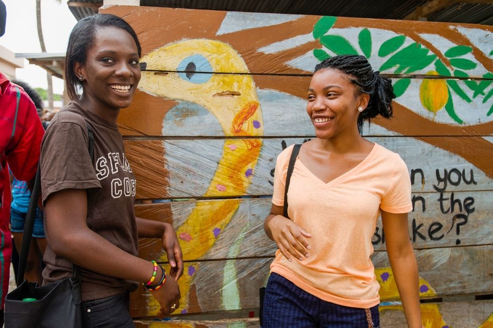 legon two smiling girls in front of mural