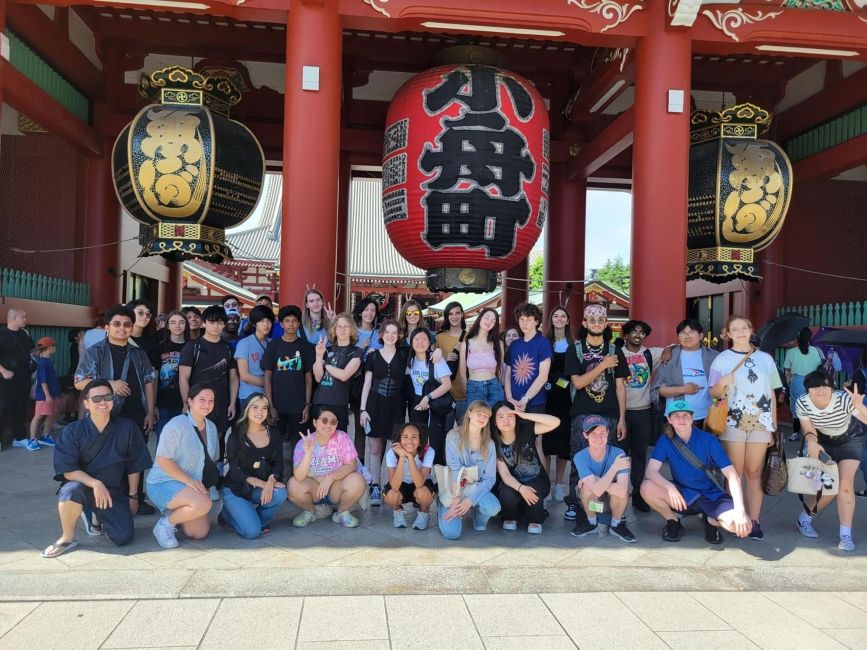 High school students standing beneath temple in Asia