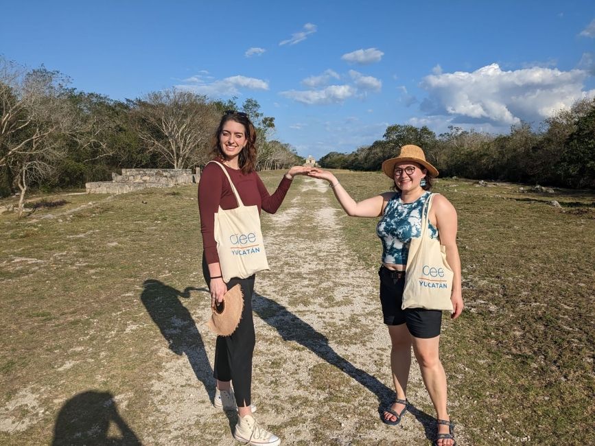 Two women with CIEE totes holding up their hands on a path in the Yucatan
