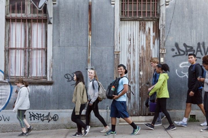 Photo of Mohamed Kilani smiling and walking with other students in front of a wall in Chile