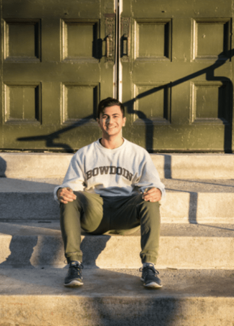 High School study Abroad student Mohamed Kilani in Bowdoin Shirt Seated on Stairs