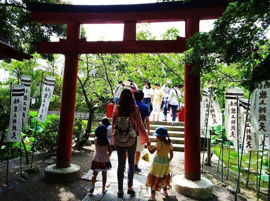 Teacher and kids in Japan strolling under a red gate