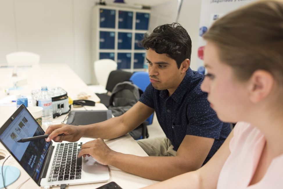 Two students sit together looking at a laptop during CIEE global internship program