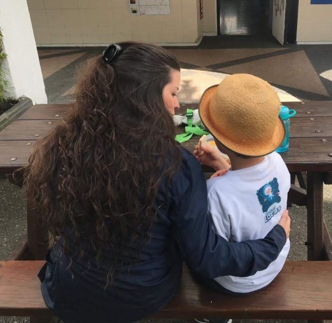 Andrea with a young students doing an activity at a table together