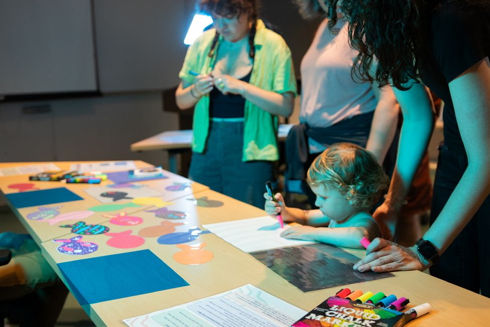 a young person (toddler) completing a craft with a marker - looks like she's making paper fish