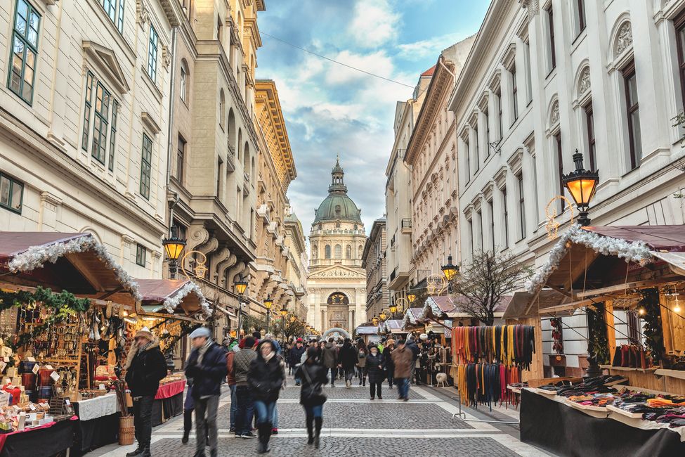 Crowd of people walking on Zrinyi Street during the Christmas holidays in Budapest at dusk.
