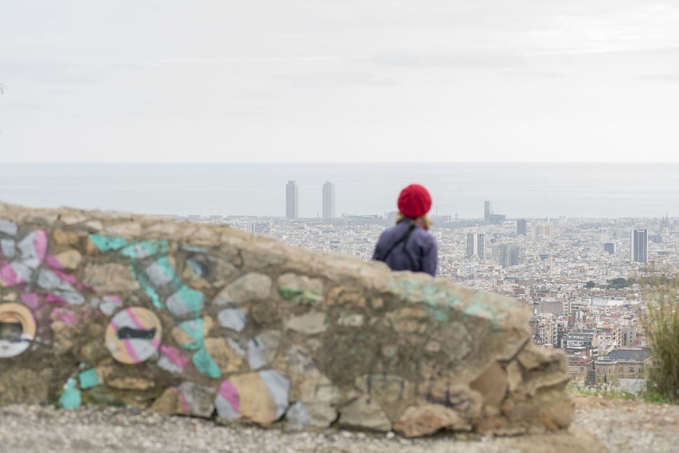 Student in red hat looking down at city skyline on hike