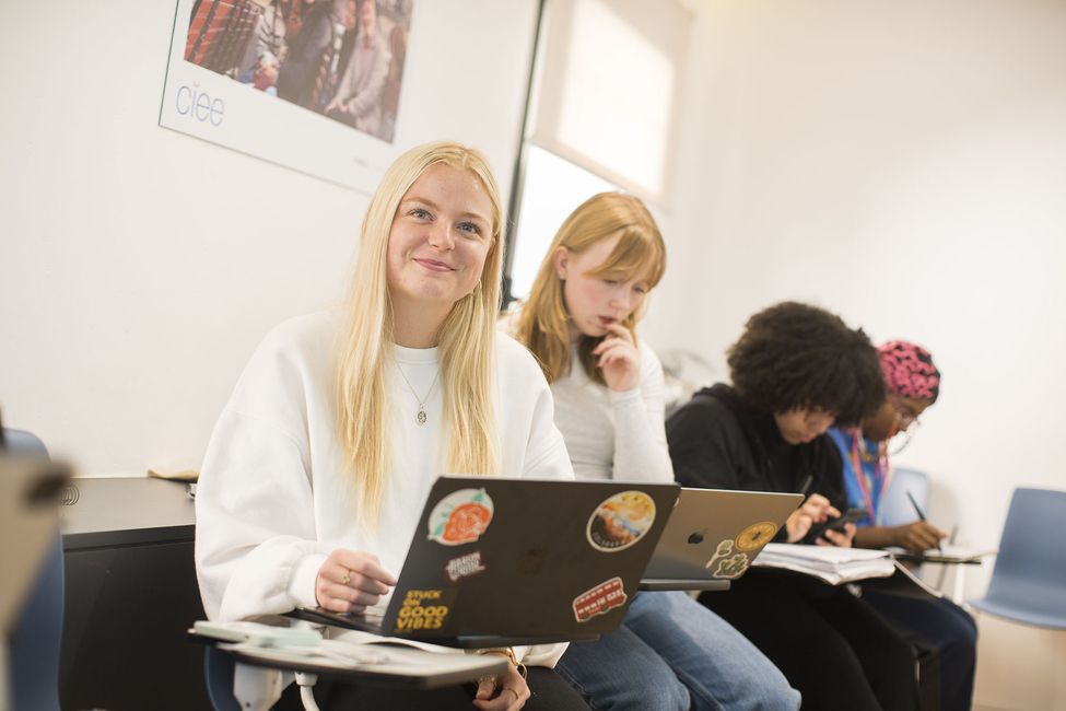 Student with laptop listening and smiling to instructor
