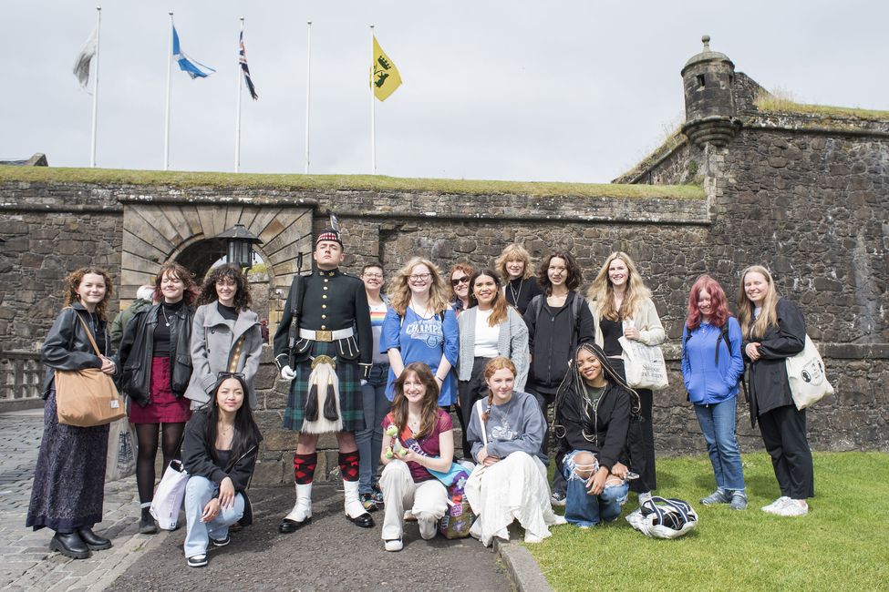 High school students studying abroad posing with bagpiper