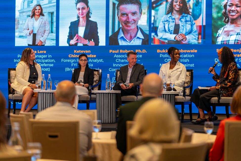 a group of 5 people on a stage speaking panel discussion