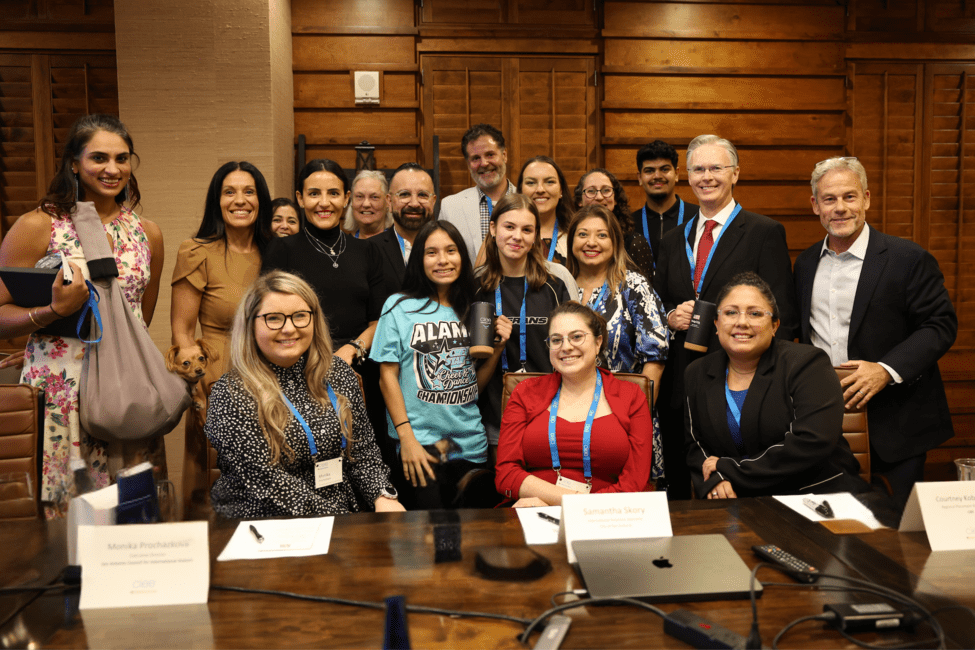Group photo of CIEE senior leadership with San Antonio partners seated and standing around a conference table.