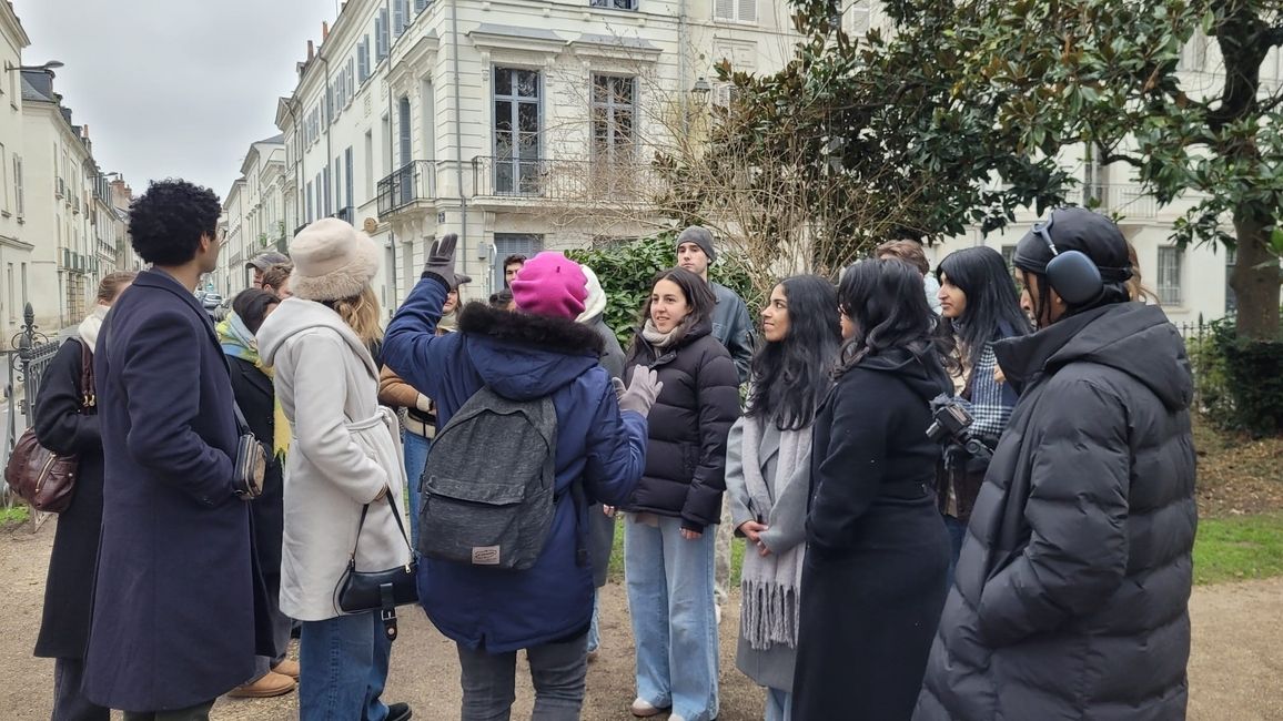 students standing in a group in Paris streets looking at a tour guide