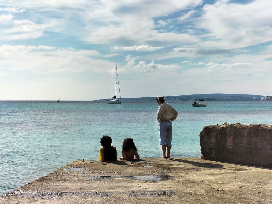 palma-three-students-relaxing-pier-sailboats