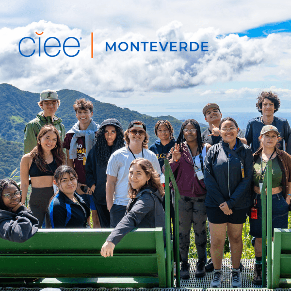 A group of 13 students standing in front of a mountain range