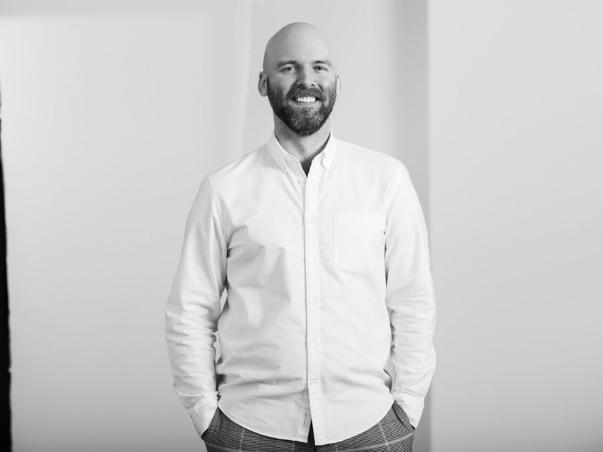 A man in a white button down shirt standing and smiling at the camera