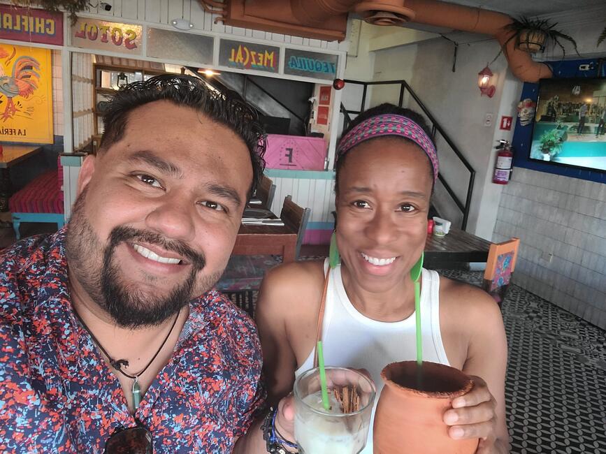 Jemise Ray De La Cruz and her husband smile while enjoying drinks together at a colorful restaurant in Juárez, Mexico.