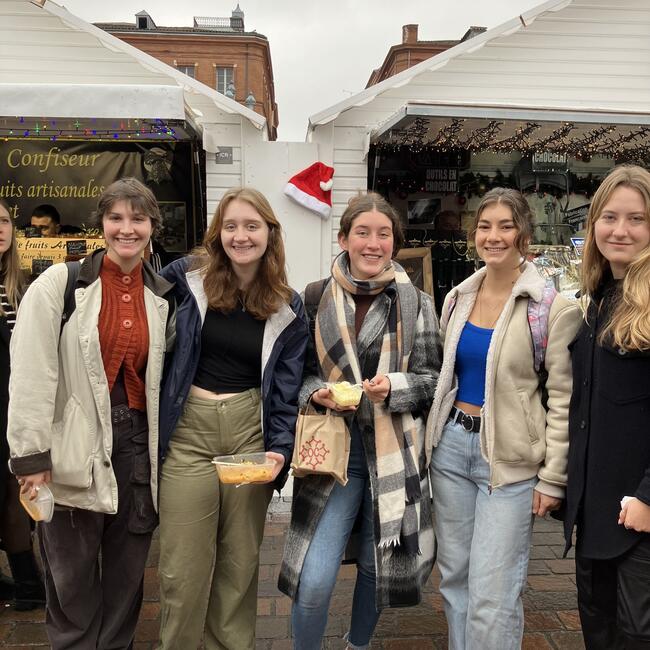 Group of female study abroad students pose at Christmas market in Toulouse, France