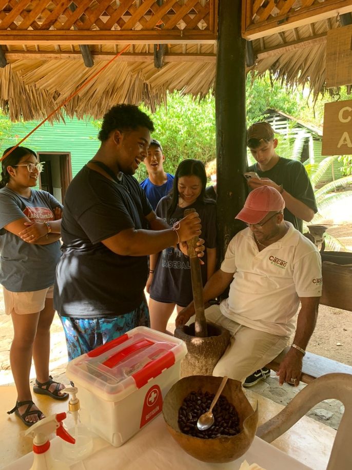 A student learning traditional cacao grinding techniques