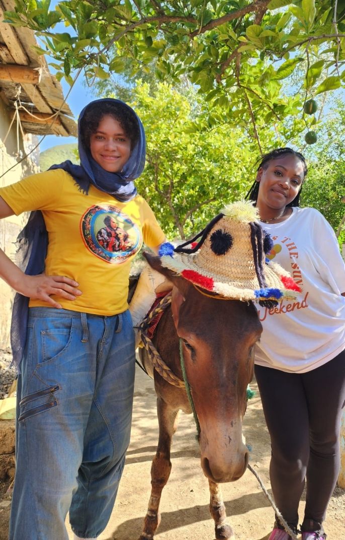 Two CIEE students standing on both sides of a donkey