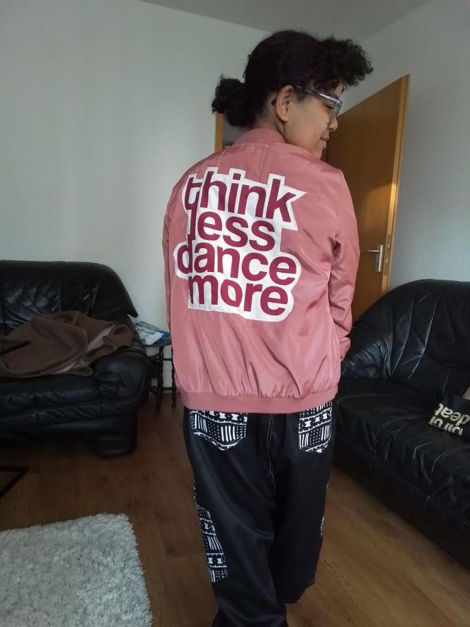 A student wearing a new jacket purchased from a local shop at Holzmarkt 25 with the text "think less dance more"