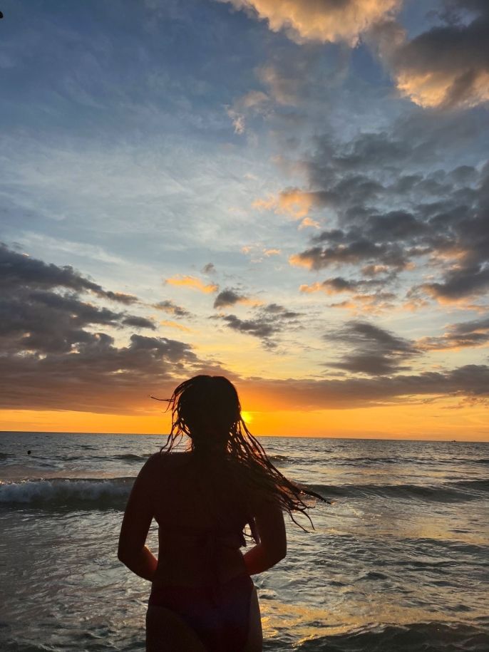 silhouette of a girl against a a sunset over the ocean 
