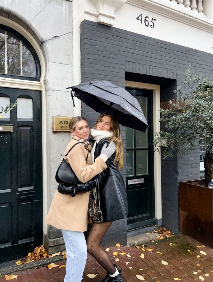 two young women hugging under an umbrella in Amsterdam