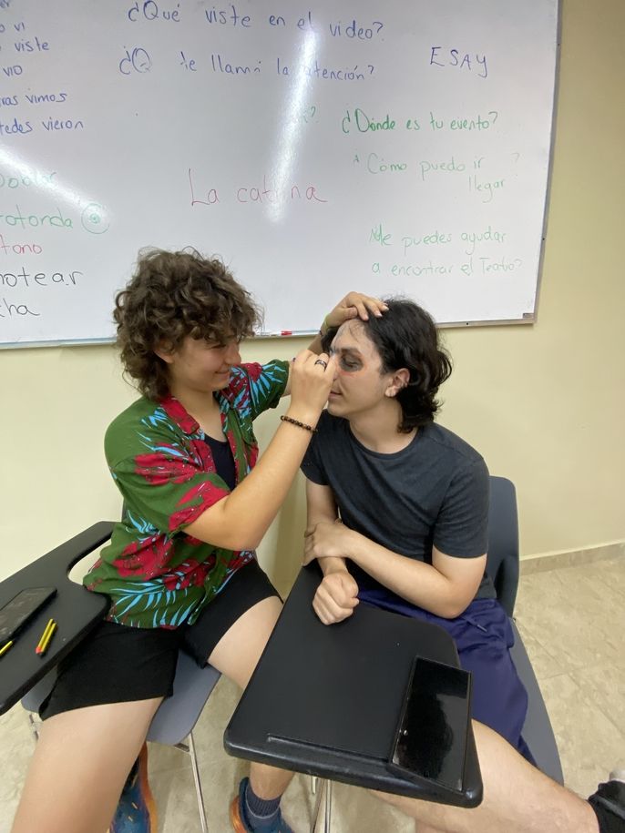 Student helping another one do a face painting.