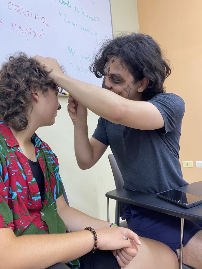 A student is helping another one with face painting.