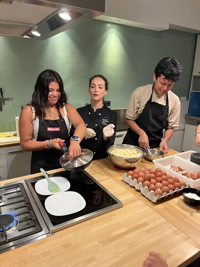 2 students cooking with the maestra/chef. 