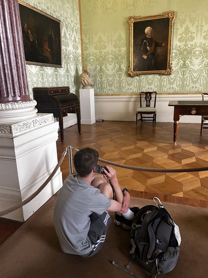 Boy sitting on floor listening to audio guide in Sanssouci