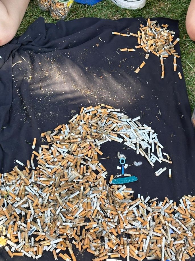Cigarette art of a surfer riding a wave on top of a black towel. 